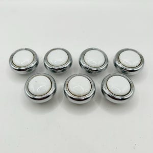 May include: Set of six white ceramic cabinet knobs with a chrome finish.