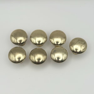 Peut inclure: Ensemble de six boutons ronds pour armoire de couleur dorée. Les boutons ont un dessus légèrement surélevé et arrondi.