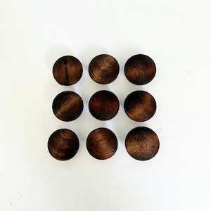 May include: A set of nine circular wooden knobs arranged in a three-by-three grid. Each knob features a dark brown finish with visible natural wood grain patterns, showcasing a smooth, rounded surface and a consistent, uniform spherical shape.