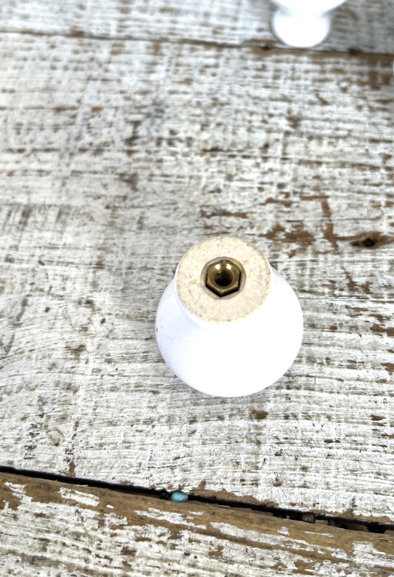 Peut inclure: Bouton de porte en c&eacute;ramique blanche avec une vis en laiton. Le bouton est rond et a une surface lisse.