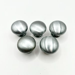 Könnte beinhalten: Fünf silberne Metall-Schrankknöpfe mit einer glatten, abgerundeten Oberfläche.