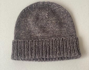 May include: A brown knitted beanie with a textured pattern. The beanie has a folded brim.