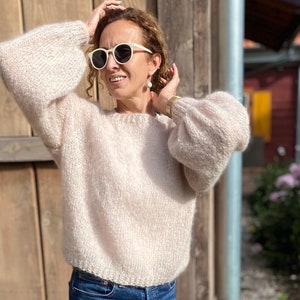 Puede incluir: Un su&eacute;ter de punto beige claro de corte holgado y mangas largas. El su&eacute;ter tiene un cuello redondo y una longitud ligeramente recortada.