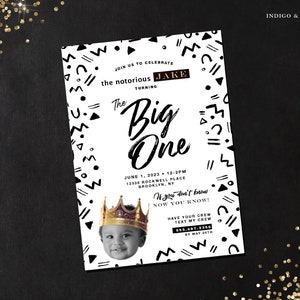 May include: Black and white birthday party invitation with a geometric pattern border. The invitation says "Join us to celebrate the notorious Jake turning The Big One". It includes the date, time, and location of the party. The invitation also includes a photo of a baby boy wearing a gold crown.
