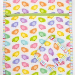 May include: A white zippered pouch with a colourful border and a repeating pattern of fuzzy chicks in various colours. The pouch has a smaller matching pouch attached to it.