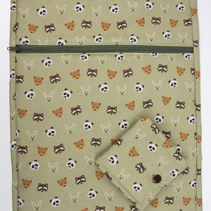 Könnte beinhalten: Eine grüne Reißverschlusstasche mit einer kleineren, passenden Tasche, die daran befestigt ist. Beide Taschen haben ein sich wiederholendes Muster aus braunen Bären, Pandas und Kaninchen.