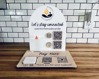 May include: A white display stand with the text "Zen Homemade Candle" and "Let's stay connected @zenhomemadecandle." Includes a candle with an orange flame, Instagram and Facebook icons, and QR codes. The base reads "Pay Here" and "Thank you for your support!"