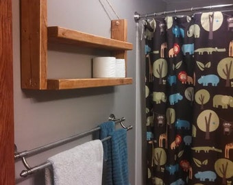 May include: A bathroom with a wooden shelf hanging from the ceiling, a double towel rack, and a shower curtain with a jungle animal print.