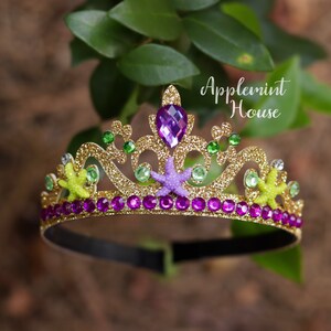 May include: Gold glitter headband with a purple gem, green and yellow starfish, and purple rhinestones. The headband says "Applemint House".