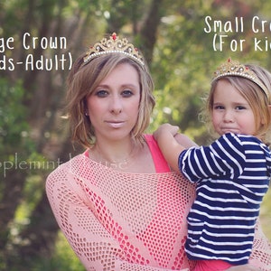 May include: Two people wearing gold crowns with red jewels. The woman is wearing a pink crocheted sweater and the girl is wearing a blue and white striped shirt. The text "Large Crown (For Kids-Adult)" is above the woman and the text "Small Crown (For kids)" is above the girl.