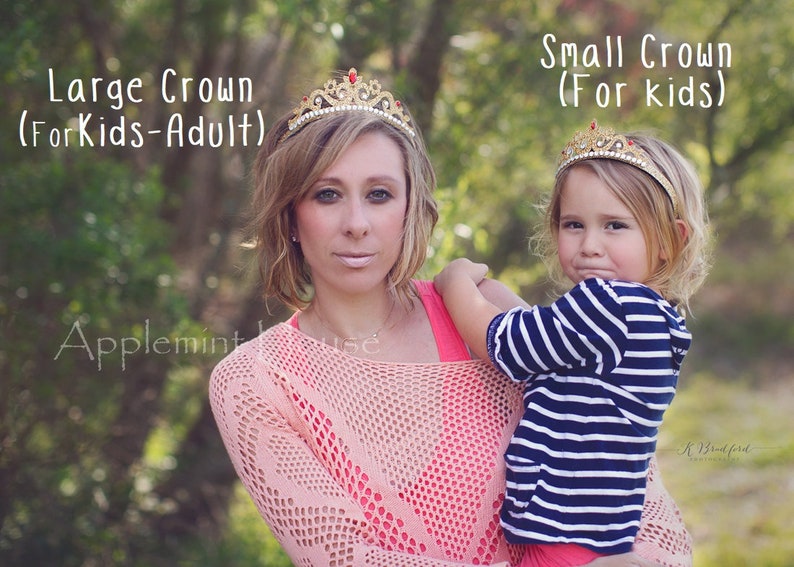 May include: Two people wearing gold crowns with red jewels. The woman is wearing a pink crocheted sweater and the girl is wearing a blue and white striped shirt. The text "Large Crown (For Kids-Adult)" is above the woman and the text "Small Crown (For kids)" is above the girl.