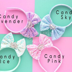 Puede incluir: Cuatro diademas con lazos de diferentes colores. Los lazos est&aacute;n hechos de lentejuelas iridiscentes y tienen un peque&ntilde;o dije de corona en el centro. Las diademas est&aacute;n etiquetadas como "Candy Lavender", "Candy Sky", "Candy Ice" y "Candy Pink".