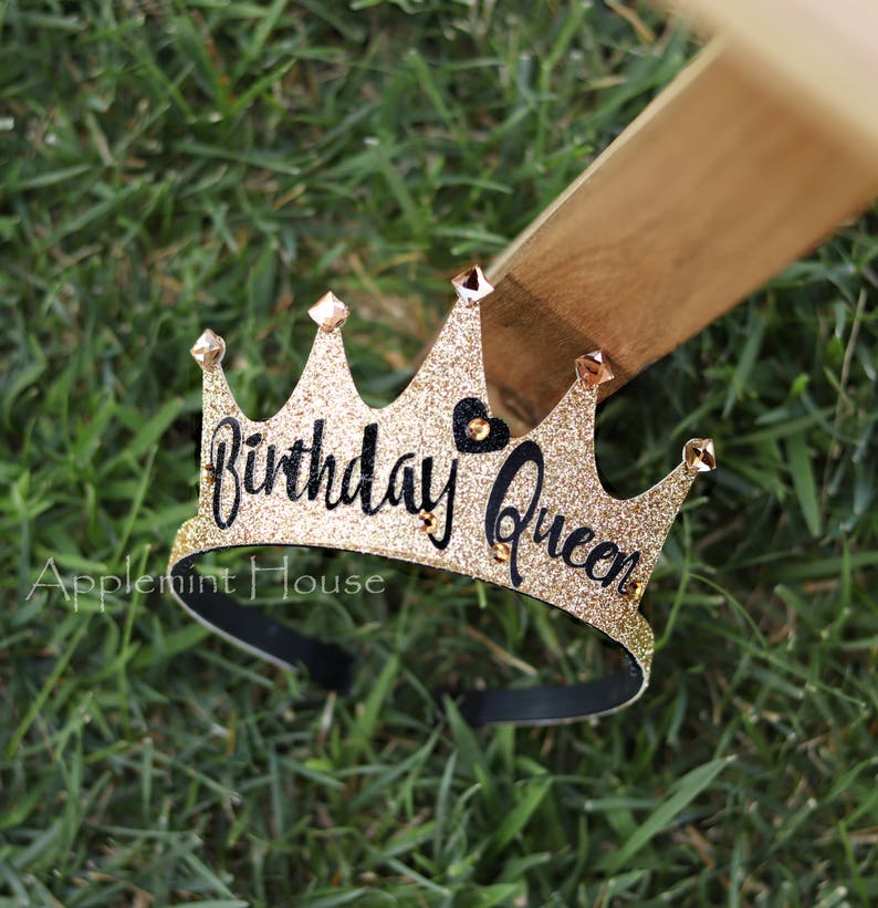 May include: Gold glitter crown headband with black lettering that says "Birthday Queen" and a small black heart. The headband is black.