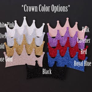 May include: A selection of glitter crowns in various colors, including white, pink, silver, gold, rose gold, lavender, red, royal blue, and black. The crowns are arranged in a row, with the colors listed below each crown. The text "*Crown Color Options*" is at the top of the image.