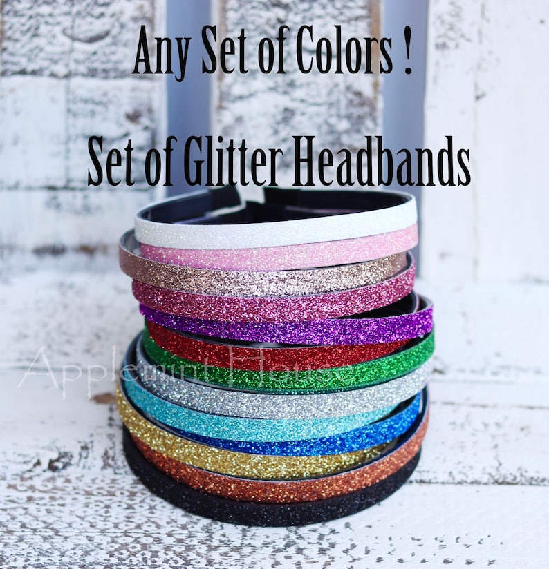 May include: A stack of glitter headbands in various colors, including white, pink, gold, red, purple, green, blue, and black. The text "Any Set of Colors! Set of Glitter Headbands" is visible above the headbands.