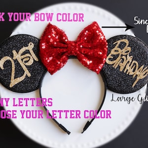 Może przedstawiać: Czarne uszy Minnie Mouse z brokatem i czerwoną kokardą z cekin&oacute;w. Na lewym uchu napis "21st" w złotym brokacie. Na prawym uchu napis "Happy Birthday" w złotym brokacie. Kokarda ma 12,7 cm szerokości.