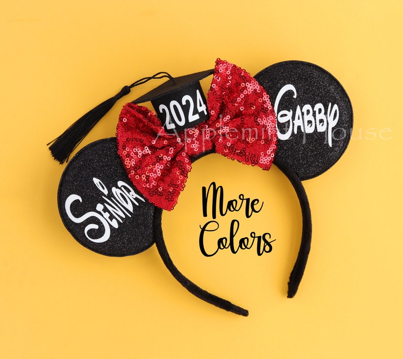 May include: Black mouse ears headband with a red sequined bow, a black graduation cap with the year 2024 on it, and the word "Senior" on one ear and "Gabby" on the other ear.