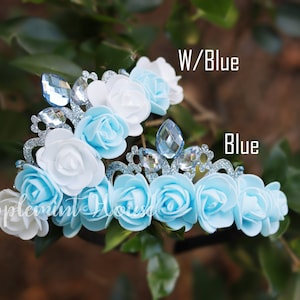 May include: Two flower crowns with blue and white fabric flowers and silver glitter trim. One crown has all blue flowers and the other has white and blue flowers. The text "W/Blue" and "Blue" are visible in the image.