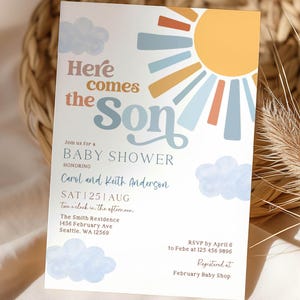Pode incluir: Convite para chá de bebé com o texto "Here comes the Son" numa fonte caprichosa. O design apresenta um sol com raios azuis e amarelos e nuvens azuis suaves. O convite inclui detalhes do evento, incluindo a data, hora e local.