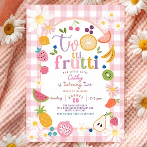 May include: A party invitation with a pink gingham background and the words "Two tti frutti" in colourful lettering. The invitation includes fruit illustrations and text that reads "Cathy is turning two." White daisies and a pink blanket surround the invitation.