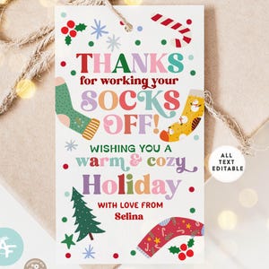 May include: A holiday gift tag with the text "THANKS for working your SOCKS OFF!" in colorful letters. The tag features illustrations of socks, a Christmas tree, and holly. The text "WISHING YOU A warm & cozy Holiday" is also included.