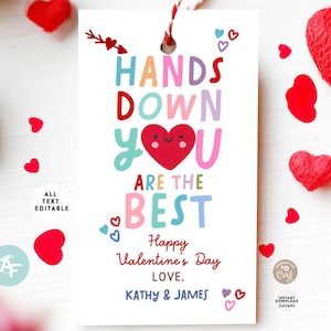 May include: A white Valentine's Day gift tag with the text "HANDS DOWN YOU ARE THE BEST". The tag has a red heart graphic and the words "Happy Valentine's Day LOVE, KATHY & JAMES". Decorative hearts and a red and white string are also visible.