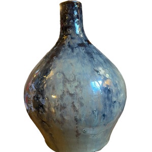 May include: A ceramic vase with a round body and a narrow neck. The vase has a blue and grey glaze with a speckled finish.