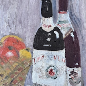 May include: Two bottles of wine, one with a white label featuring a red rose and the text "LILY PLEAS", the other with a dark label. The bottles are in front of a red and yellow fruit.