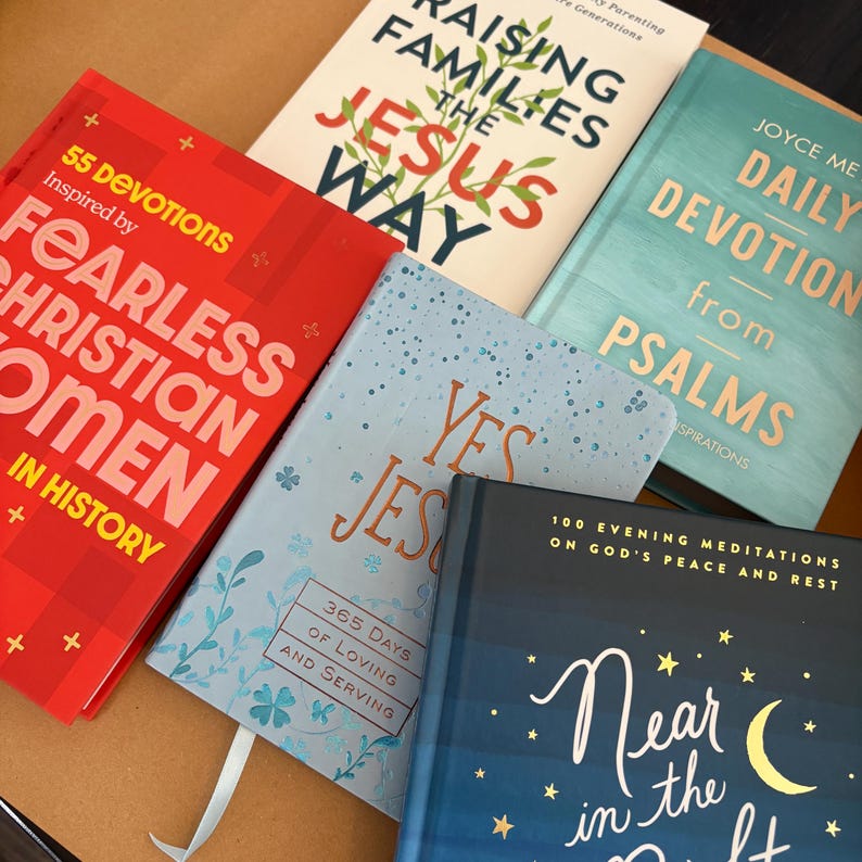 K&ouml;nnte beinhalten: Eine Sammlung von Hardcover-B&uuml;chern mit Titeln wie "Fearless Christian Women in History", "Raising Families the Jesus Way" und "Daily Devotion from Psalms". Die B&uuml;cher sind in verschiedenen Farben, darunter Rot, Blau und T&uuml;rkis.