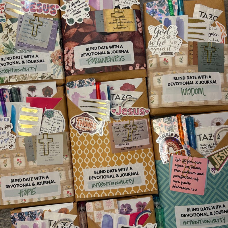 K&ouml;nnte beinhalten: Eine Sammlung von verpackten Andachtsjournalen mit dekorativen Aufklebern und Stiften. Jedes Journal ist mit einem Thema wie "Vergebung", "Weisheit" und "Absicht" versehen. Die Journale sind mit Kreuzen und inspirierenden Zitaten verziert.