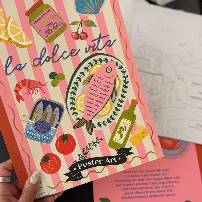 May include: A notebook with a pink and white striped cover featuring the words "la dolce vita." Illustrations of Italian food, including a pink fish, tomatoes, and sardines, are displayed. The words "Poster Art" are also visible.