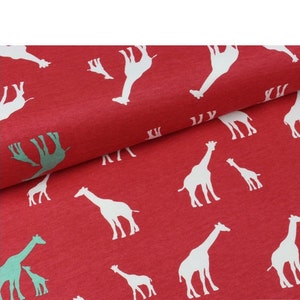 May include: Red fabric with a white giraffe print. The giraffes are in various sizes and positions, some are facing left and some are facing right. The fabric has a textured surface.