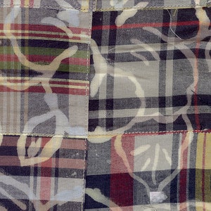 Op de afbeelding: Een patchwork stof met een ruitpatroon in tinten rood, blauw en wit. De stof heeft een subtiel bloemenpatroon dat erop is gedrukt.