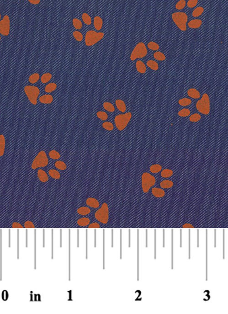 Peut inclure: Un tissu bleu avec un motif r&eacute;p&eacute;t&eacute; d'empreintes de pattes orange. Une r&egrave;gle est incluse pour montrer l'&eacute;chelle du tissu.