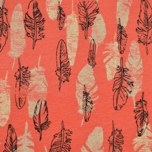May include: Coral pink fabric with a repeating pattern of black feather silhouettes. The feathers are stylized and have a slightly distressed look.