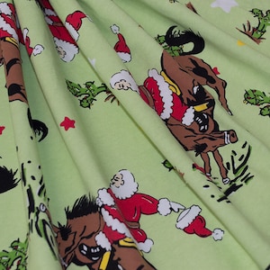 May include: Green fabric with a repeating pattern of Santa Claus riding a bucking horse. The fabric has a white star and red star pattern.