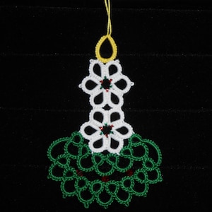 May include: A white and green crocheted Christmas ornament with a yellow loop at the top. The ornament features two white flowers with red centers and a green, leafy design.