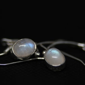 May include: A pair of silver earrings with oval-shaped moonstone gemstones. The earrings have a simple design and are perfect for everyday wear.