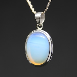 May include: A silver chain necklace with a pendant featuring a large oval-shaped opal gemstone. The opal is a light blue color with a hint of orange.