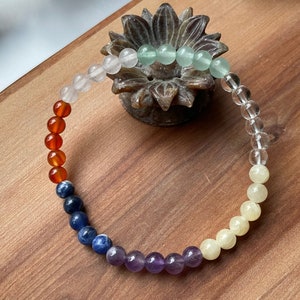 Peut inclure: Un bracelet en perles colorées avec sept couleurs de pierres différentes. Le bracelet est fait de cornaline, de lapis-lazuli, d'améthyste, de quartz clair, d'aventurine, de citrine et de quartz rose.