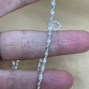 May include: A silver chain necklace with a twisted, diamond-cut design.