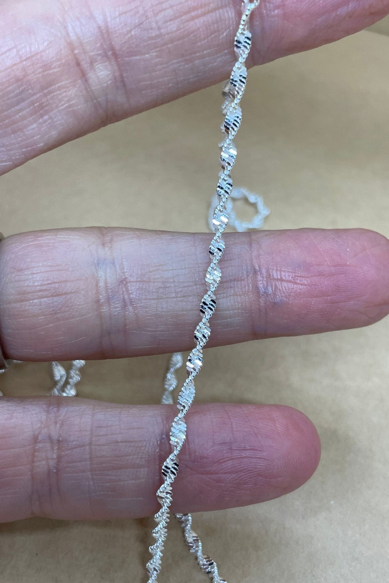 May include: A silver chain necklace with a twisted, diamond-cut design.