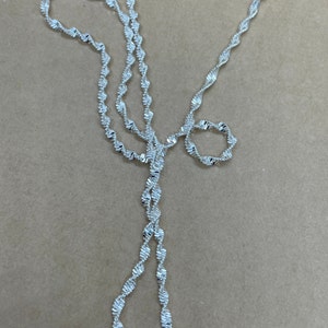 May include: A silver chain necklace with a twisted design. The chain is made of small, linked metal pieces.