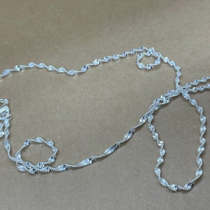 May include: A silver chain necklace with a twisted design. The chain is about 20 inches long.