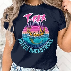 May include: A navy blue t-shirt with a graphic of a dinosaur swimming and the text "T-Rex Hates Backstroke".