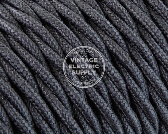 May include: Close-up of black braided cloth-covered electrical cord. The cord is textured and has a subtle sheen. The cord is labeled "Antique Style Vintage Electric Supply Modern Function".