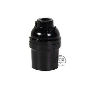 May include: Black Bakelite E26 light bulb socket. The socket is made of black plastic and has a threaded opening for a light bulb.
