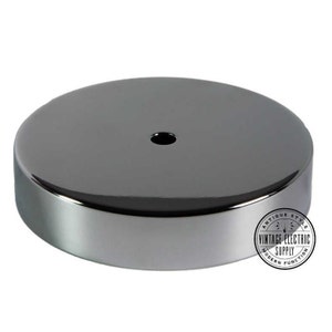 May include: A round, polished, dark gray metal ceiling canopy with a central hole. The canopy has a smooth, reflective surface and a rounded edge. The Vintage Electric Supply logo is visible on the right side.