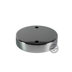 May include: A round, silver ceiling plate with two holes for electrical wiring. The plate is made of metal and has a smooth, polished finish.
