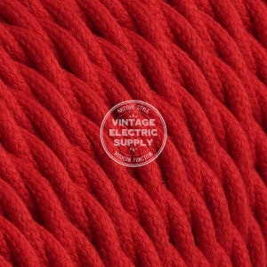 Puede incluir: Primer plano de un cable eléctrico rojo trenzado. El cable está tejido apretadamente y tiene una apariencia texturizada. Un logotipo circular blanco con el texto "ANTIQUE STYLE VINTAGE ELECTRIC SUPPLY MODERN FUNCTION" es visible.